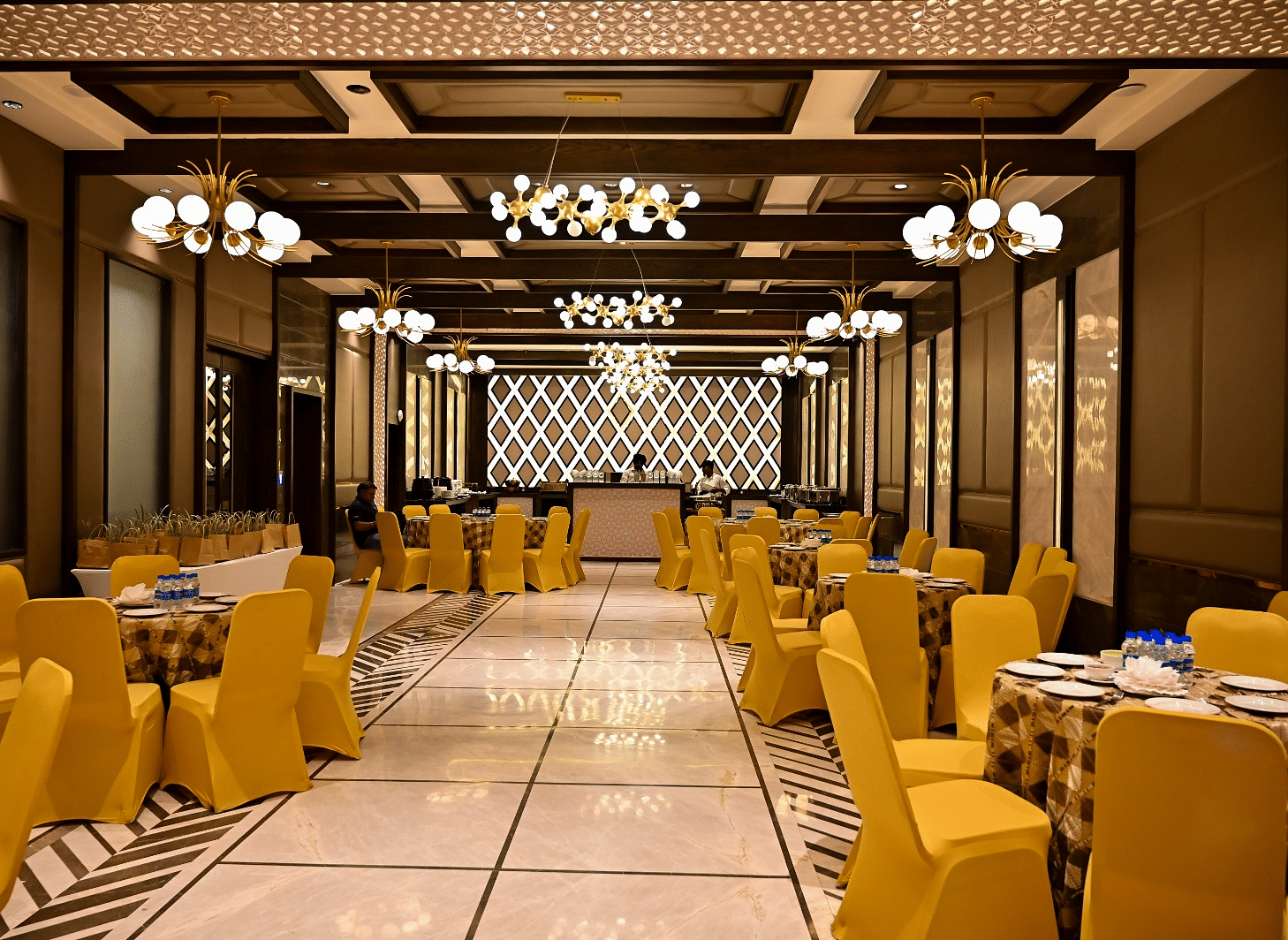 Event space with round tables and chairs arranged, featuring fancy lights hanging from the ceiling at  BluSalzz Residence, Amritsar